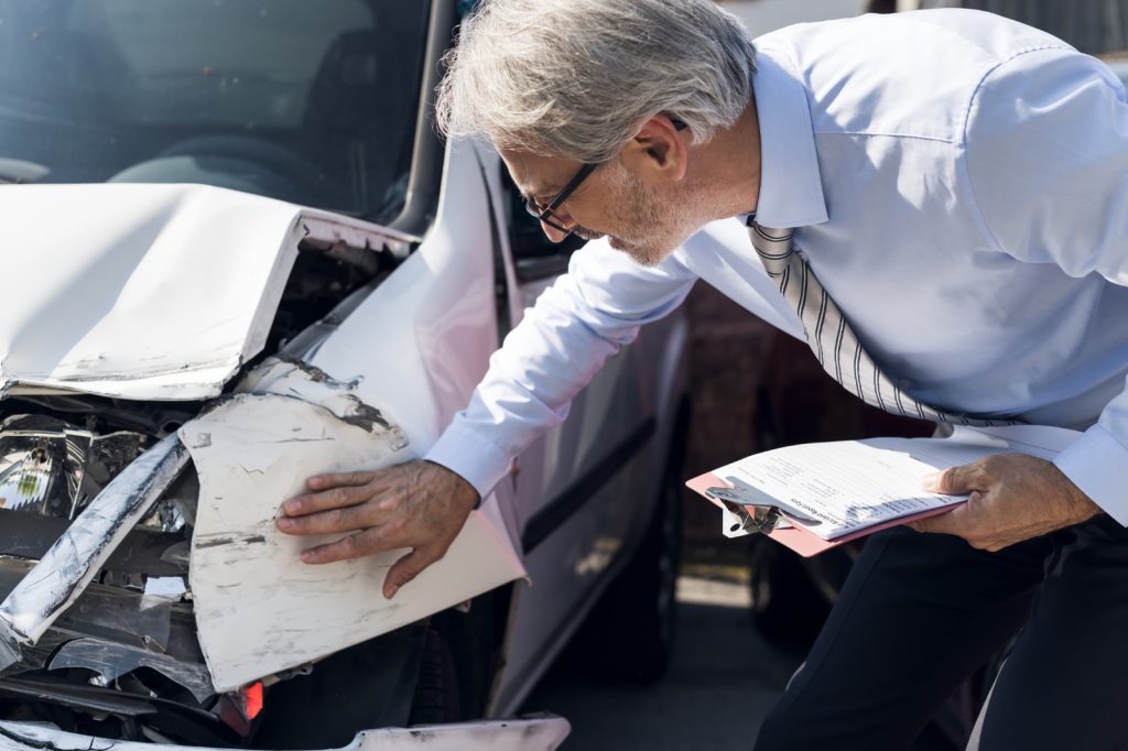 Schade-expert inspecteert autoschade en noteert bevindingen op een schadeformulier