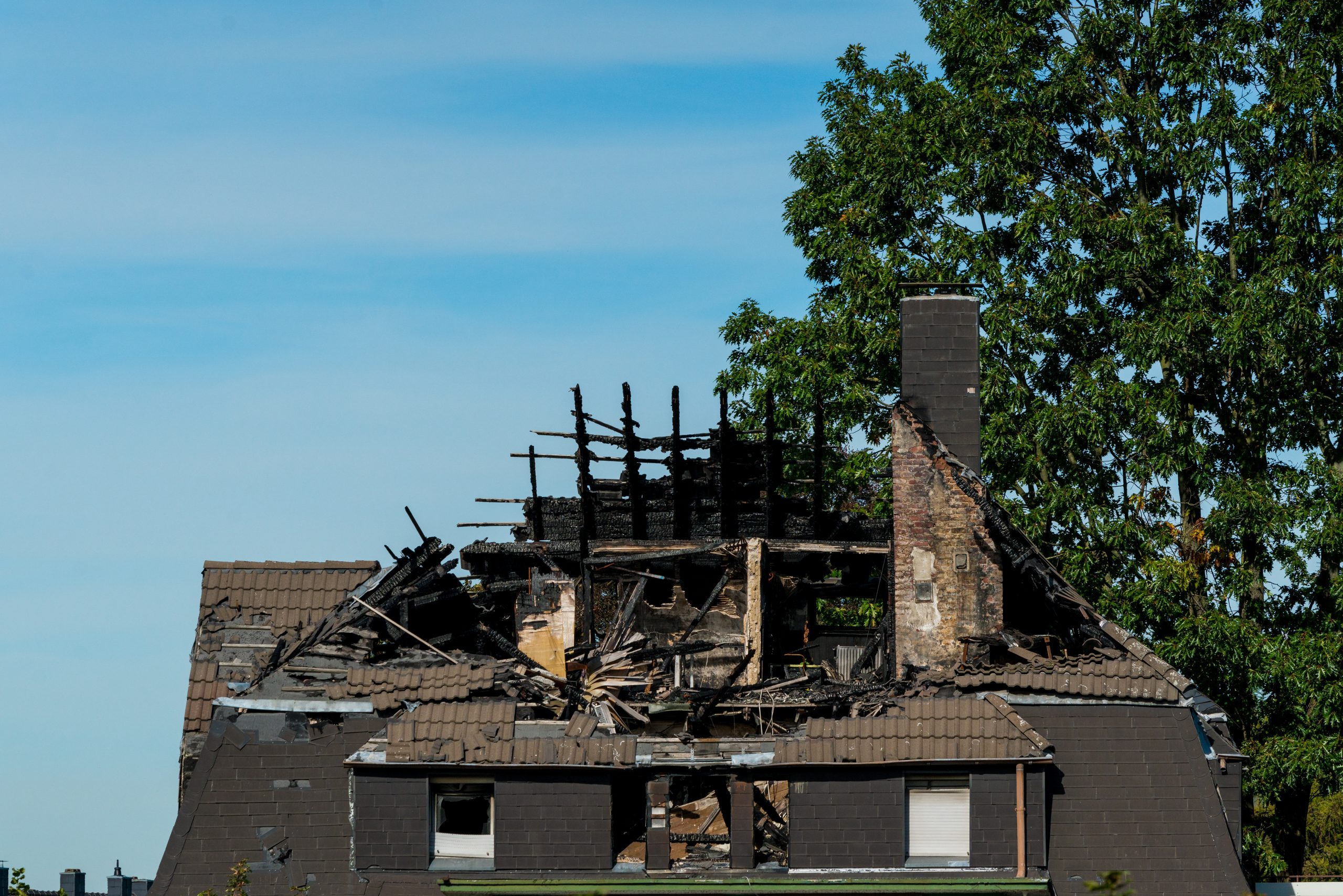 Uitgebrande woning met zwaar beschadigd dak en zwartgeblakerde dakconstructie na brand