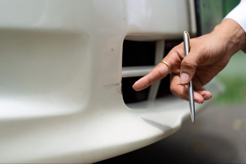 Tegenexpertise bij autoschade: expert bekijkt krassen op bumper na schadegeval