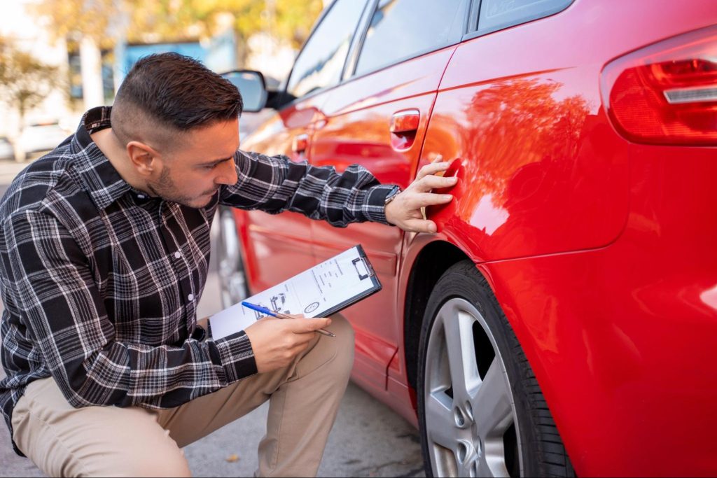 Tegenexpertise bij autoschade: onafhankelijke schade-expert controleert schade aan rode auto
