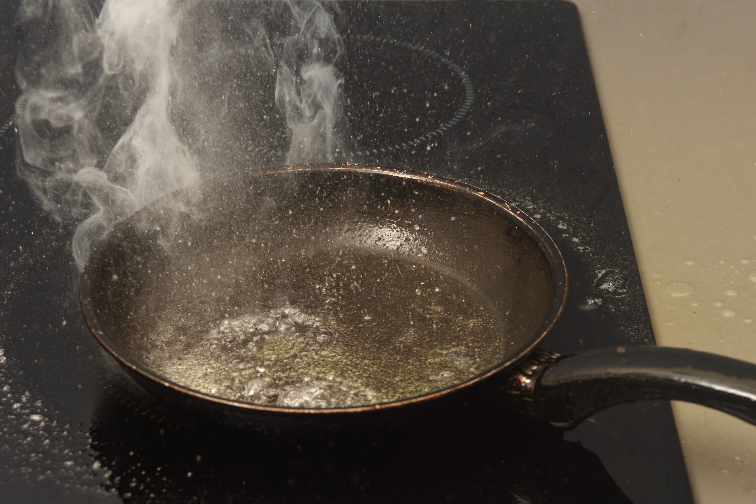 Oververhitte pan met rook op het fornuis als voorbeeld van brandgevaar bij koken zonder toezicht.